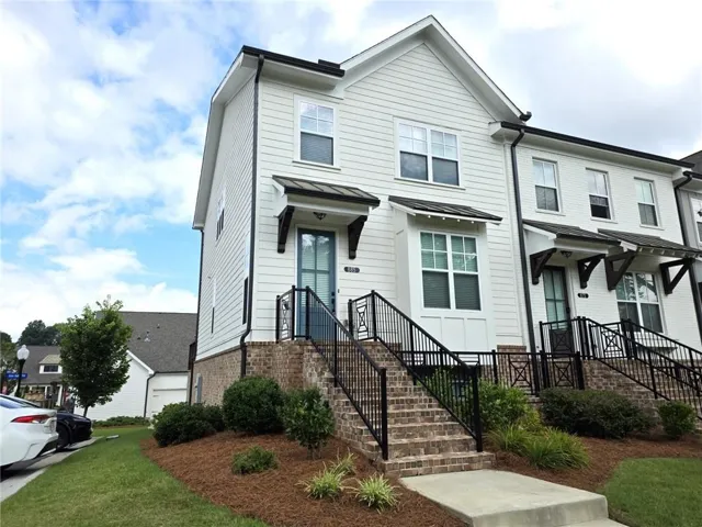 White siding exterior with black gutters, brick foundation, and a concrete walkway