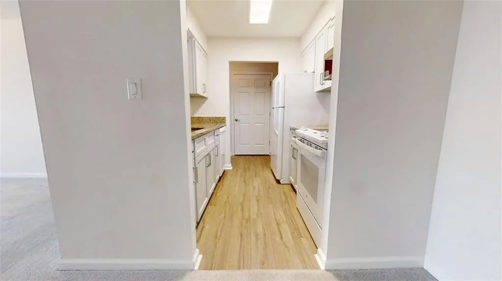 Kitchen with white cabinets, white appliances, and light stone countertops