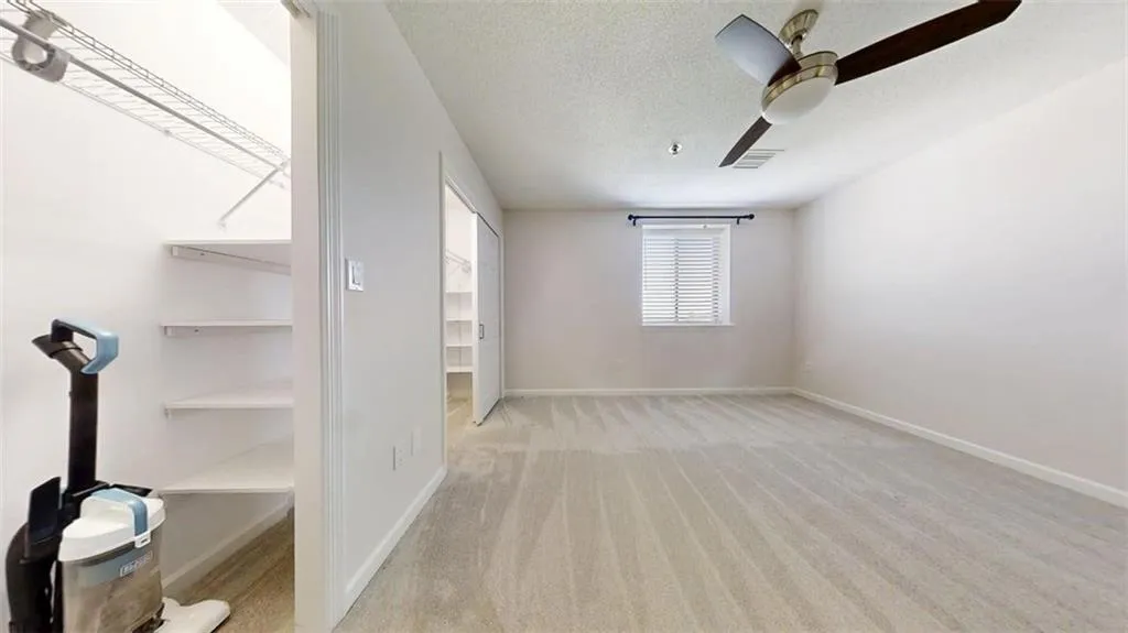 Unfurnished bedroom with a textured ceiling, light carpet, and ceiling fan