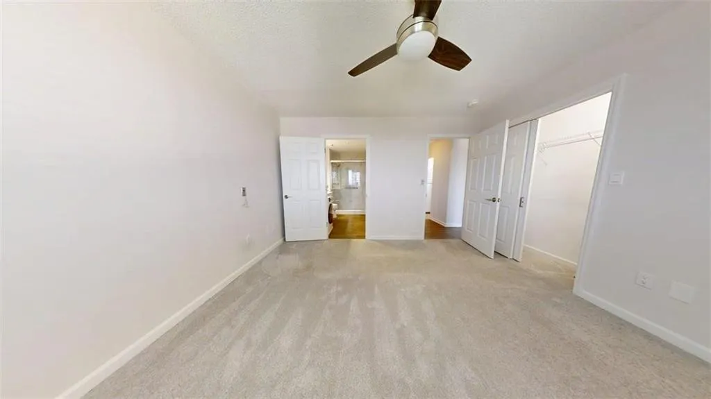 Unfurnished bedroom featuring light carpet, a closet, connected bathroom, a ceiling fan, and a textured ceiling