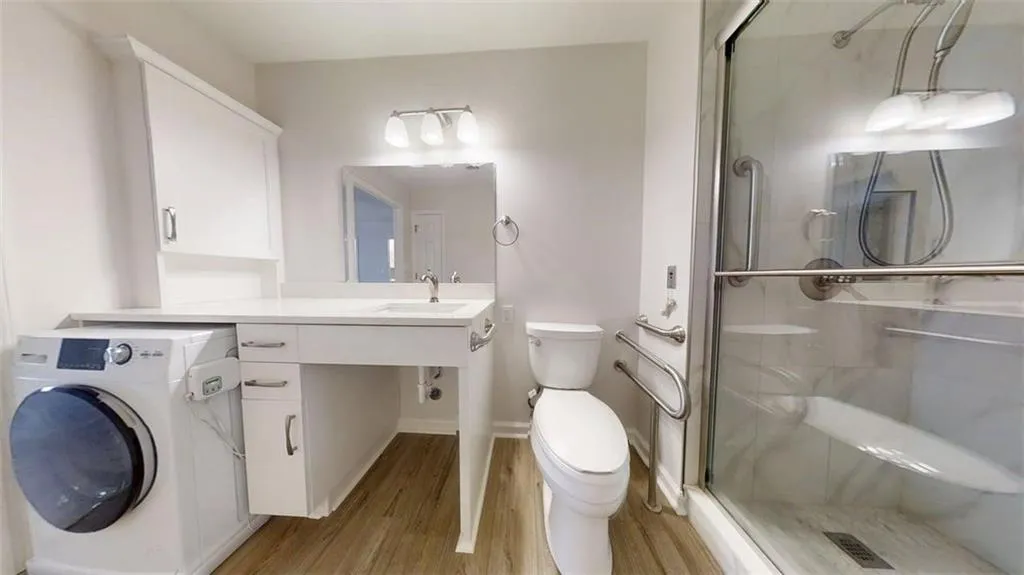 Full bathroom featuring washer / clothes dryer, vanity, a shower stall, and light wood-style floors