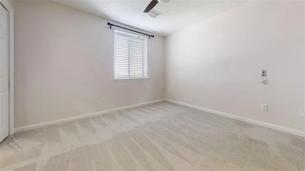 Spare room featuring light carpet, ceiling fan, and a textured ceiling