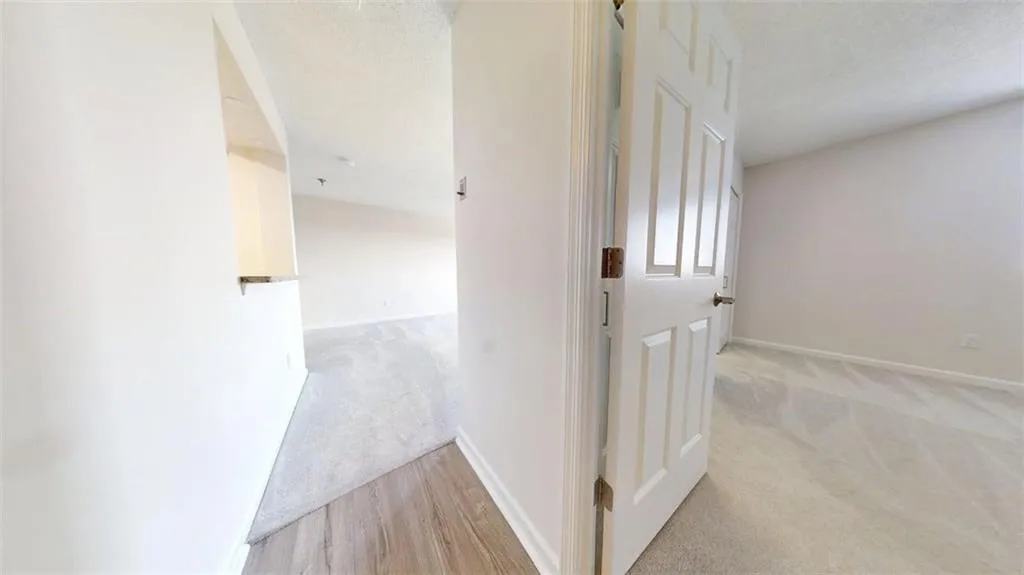 Corridor with light colored carpet and a textured ceiling