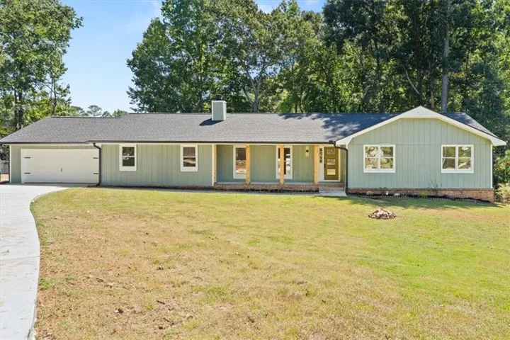 Ranch-style exterior with light green siding, covered front porch with wood columns, and an attached two-car garage