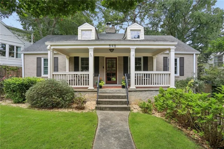 Brick exterior with a covered front porch, white railing, and column supports