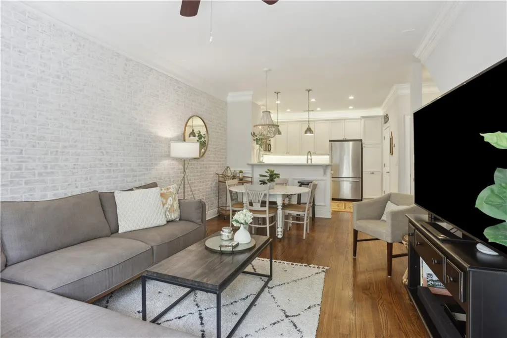 Living area with crown molding, brick wall, a ceiling fan, and dark wood-style floors