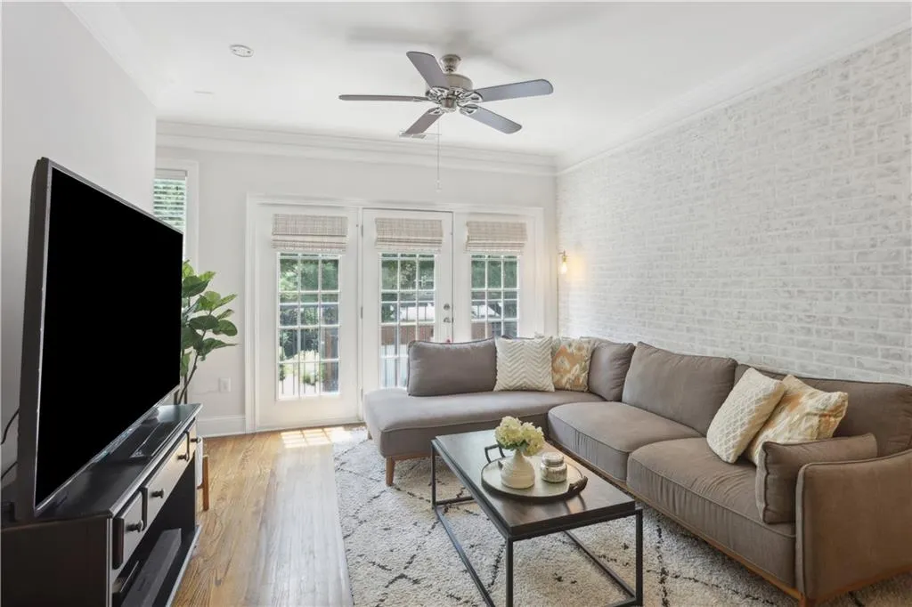 Living room with a ceiling fan, hardwood / wood-style flooring, and crown molding
