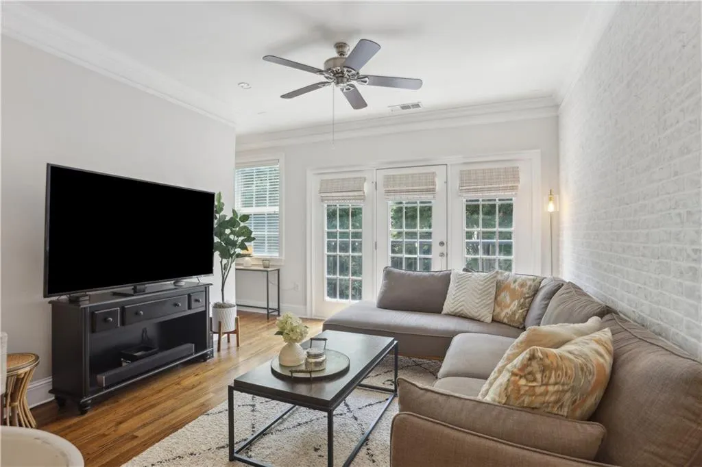 Living room featuring wood finished floors, a ceiling fan, and ornamental molding
