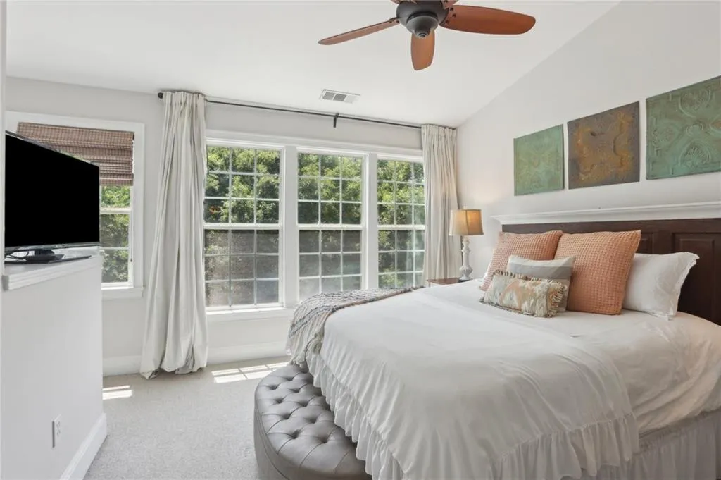 Bedroom with carpet, multiple windows, vaulted ceiling, and a ceiling fan