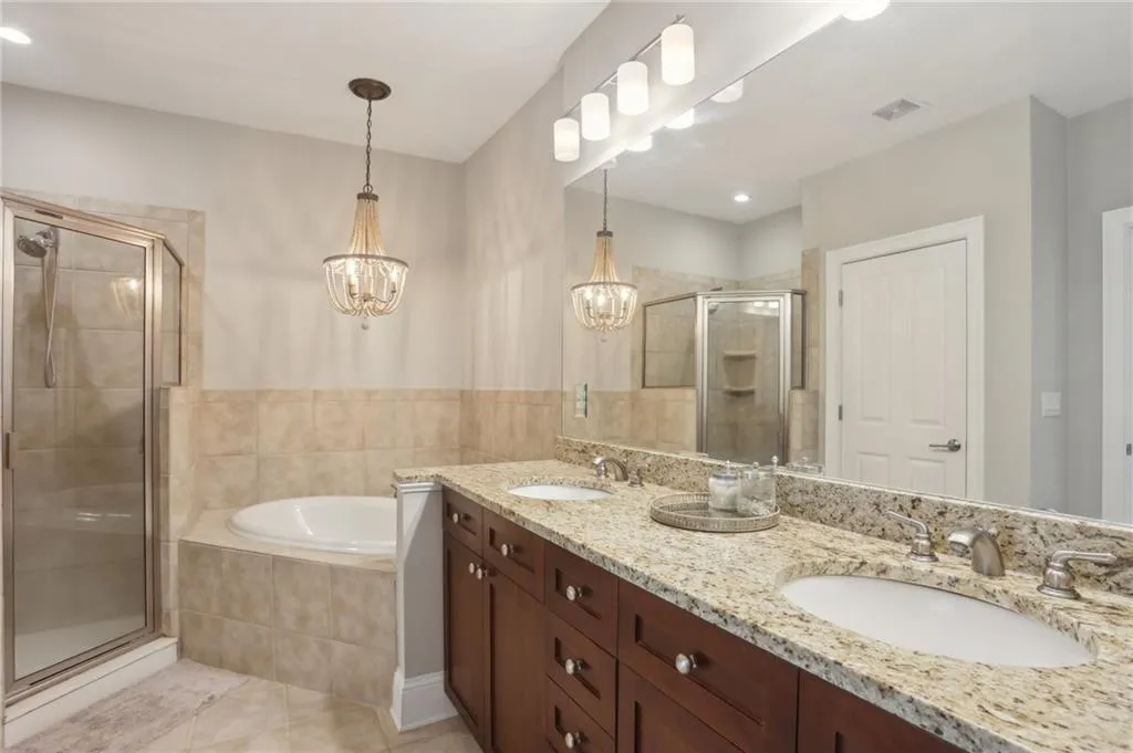 Full bath featuring a stall shower, a chandelier, a bath, double vanity, and tile patterned flooring