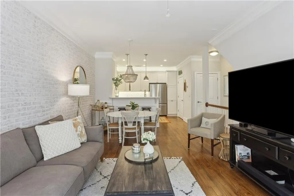 Living area with brick wall, light wood-style flooring, recessed lighting, and crown molding