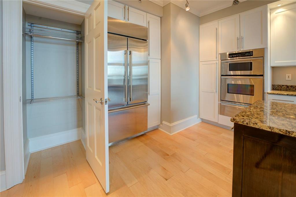 Kitchen with white cabinets, appliances with stainless steel finishes, light stone countertops, and light hardwood / wood-style flooring