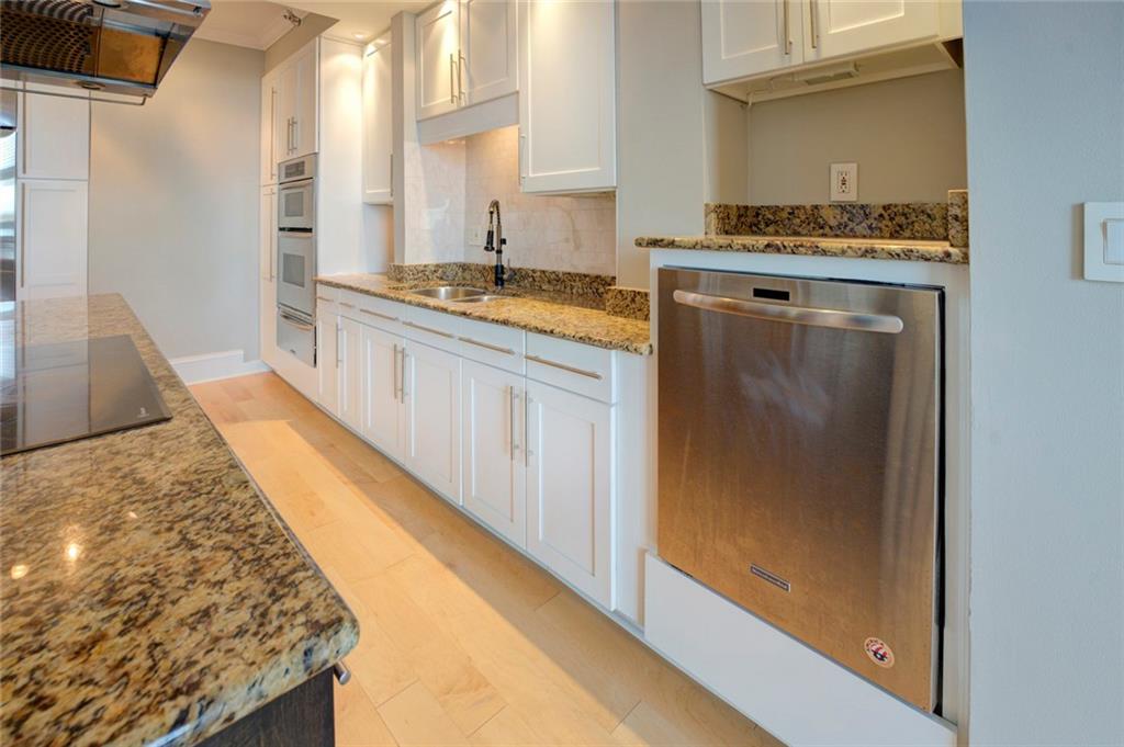 Kitchen with white cabinets, appliances with stainless steel finishes, light stone counters, backsplash, and sink