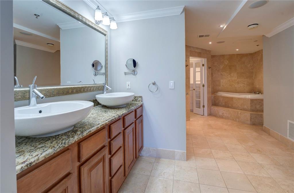 Bathroom with crown molding, tiled bath, dual vanity, and tile flooring