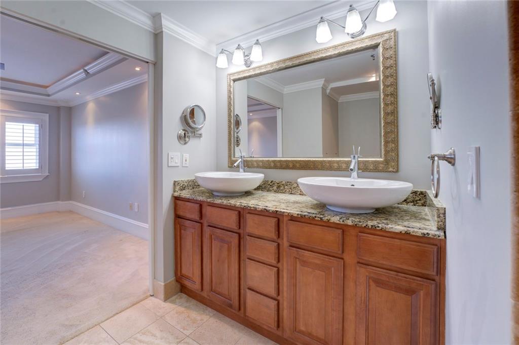 Bathroom with ornamental molding, double sink vanity, tile flooring, and a raised ceiling
