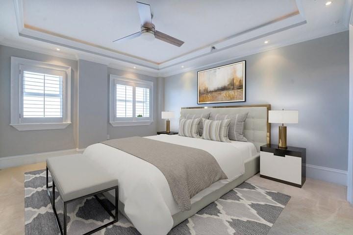 Bedroom with a tray ceiling, ceiling fan, ornamental molding, and light carpet