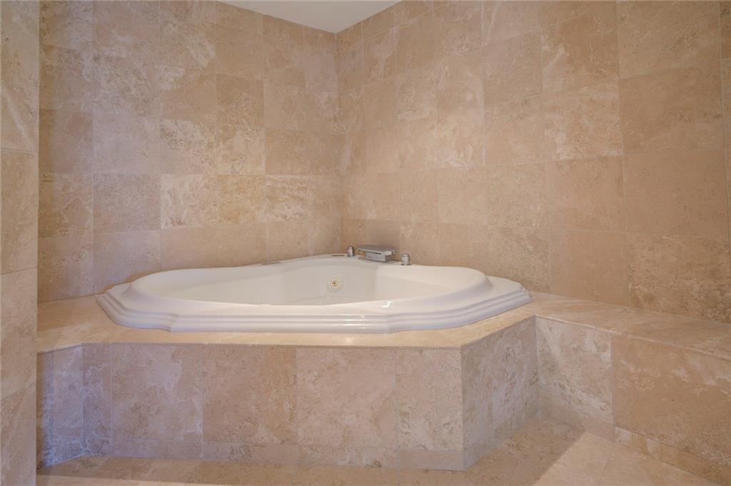 Bathroom with tile walls, a relaxing tiled bath, and tile floors