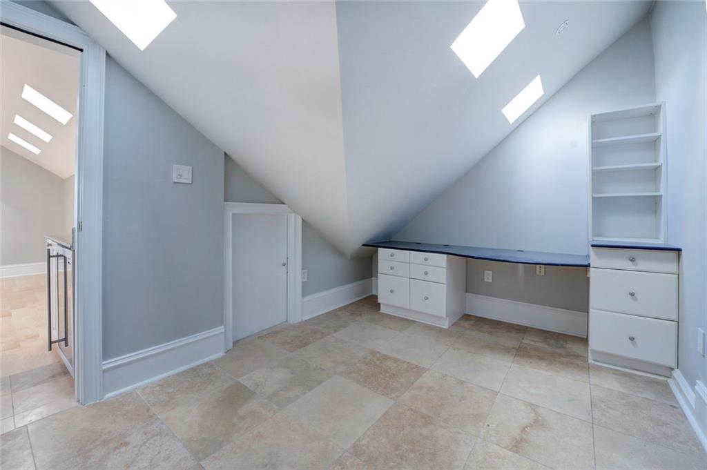 Bonus room with vaulted ceiling with skylight and light tile floors