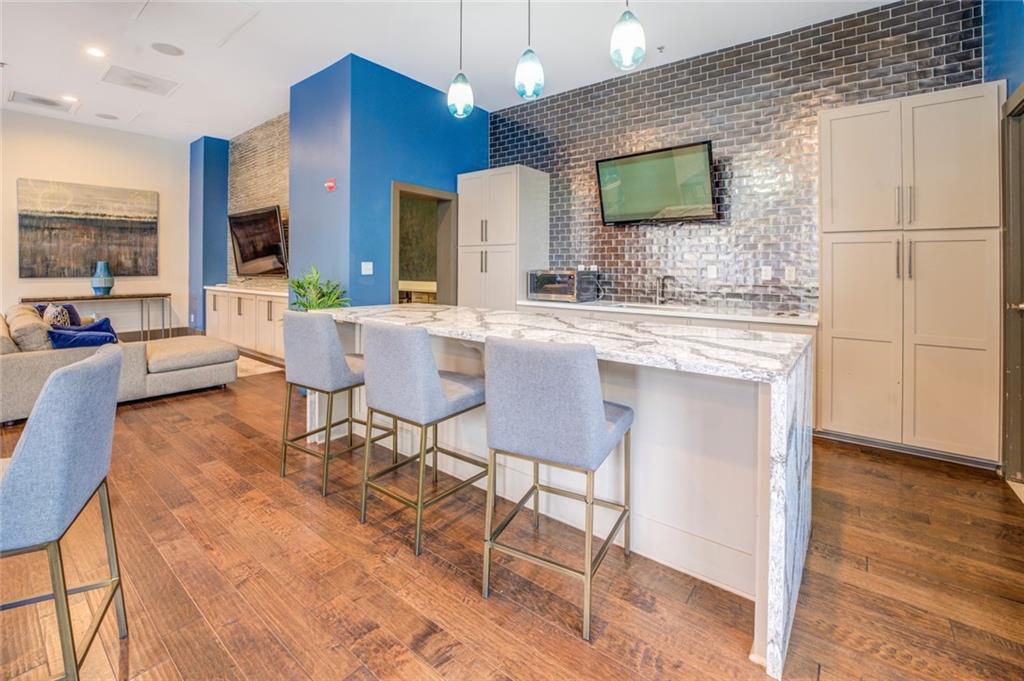 Kitchen featuring a kitchen breakfast bar, dark hardwood / wood-style flooring, white cabinetry, decorative light fixtures, and a center island
