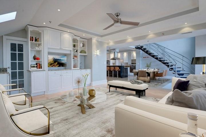 Living room with ceiling fan, a tray ceiling, and a skylight