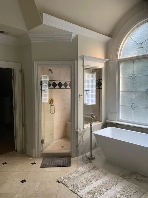 Bathroom with crown molding, shower with separate bathtub, and tile patterned floors