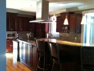 Kitchen with backsplash, light hardwood / wood-style flooring, wall chimney exhaust hood, pendant lighting, and a breakfast bar