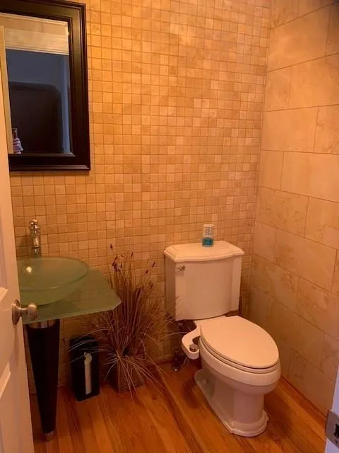 Bathroom with tile walls, hardwood / wood-style flooring, sink, and toilet