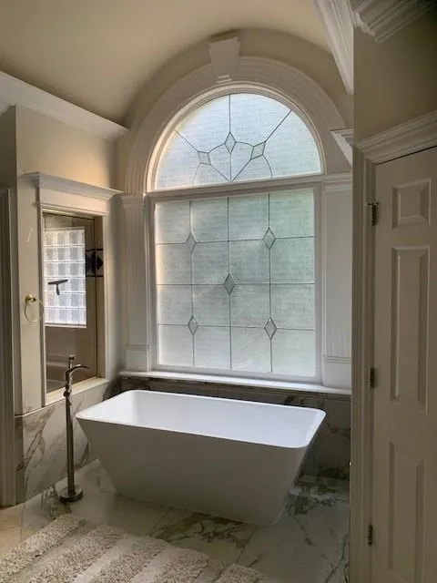 Bathroom featuring tile patterned flooring, plenty of natural light, a bathing tub, and ornamental molding