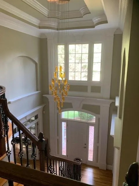 Foyer featuring hardwood / wood-style flooring, plenty of natural light, a tray ceiling, and a chandelier