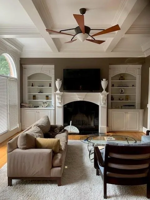 Living room with ceiling fan, ornamental molding, wood-type flooring, and coffered ceiling