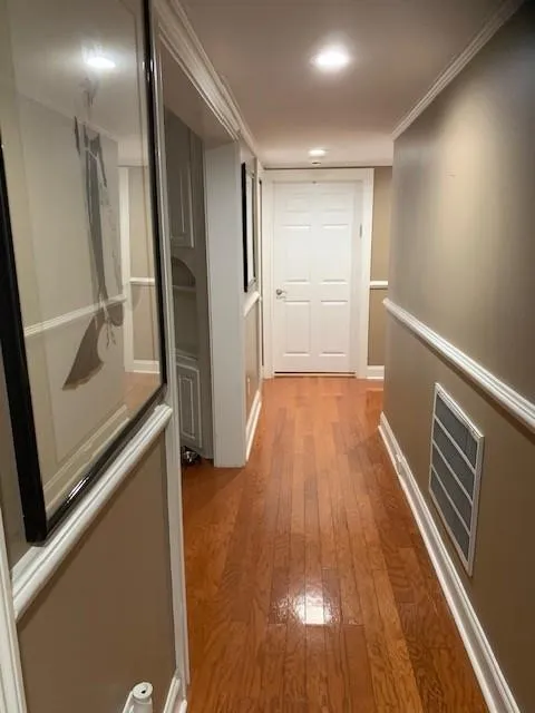 Hall with light wood-type flooring and ornamental molding
