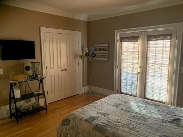 Bedroom featuring a closet, light hardwood / wood-style flooring, crown molding, and french doors