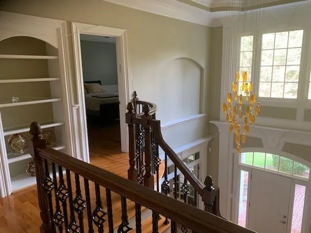 Stairs with hardwood / wood-style flooring, an inviting chandelier, crown molding, and a wealth of natural light