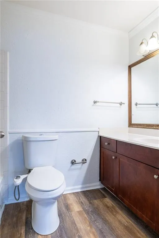 Bathroom with crown molding, wood finished floors, vanity, and toilet