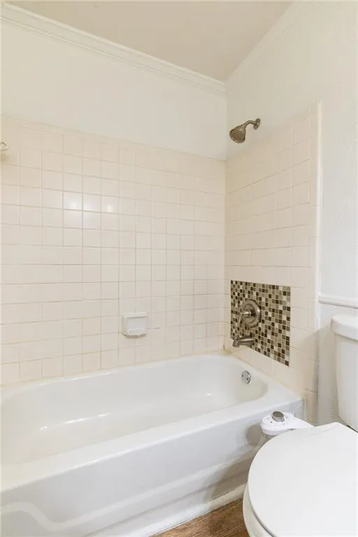 Bathroom featuring crown molding, shower / bathtub combination, and toilet
