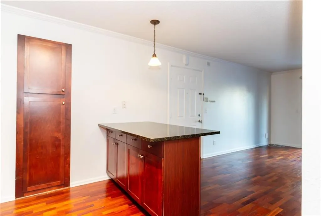 Kitchen with dark wood-style floors, crown molding, baseboards, pendant lighting, and a peninsula