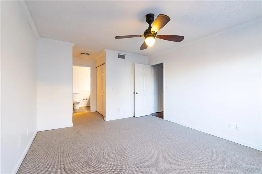 Spare room featuring carpet, visible vents, crown molding, baseboards, and ceiling fan