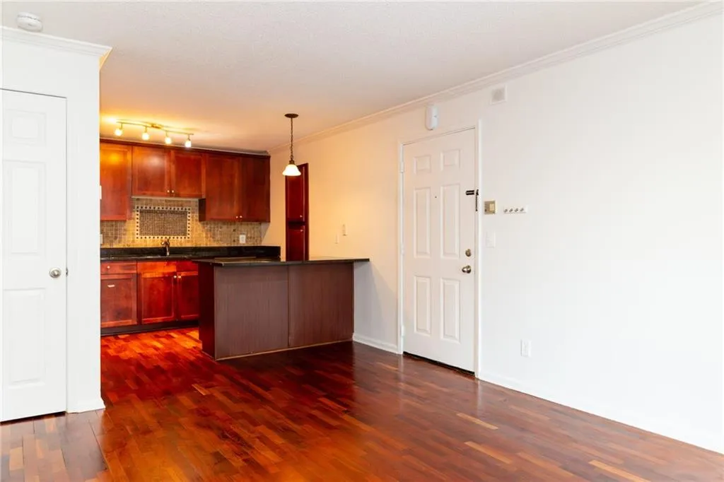 Kitchen with dark countertops, a sink, a peninsula, tasteful backsplash, and dark wood-style flooring