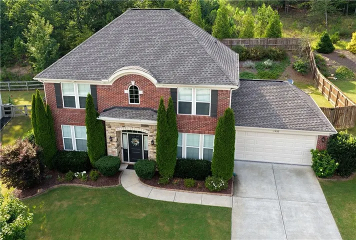 Brick facade with stone accents, arched entryway, and mature landscaping