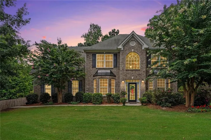 Brick-clad exterior featuring a prominent arched window, bay window, and dark shutters