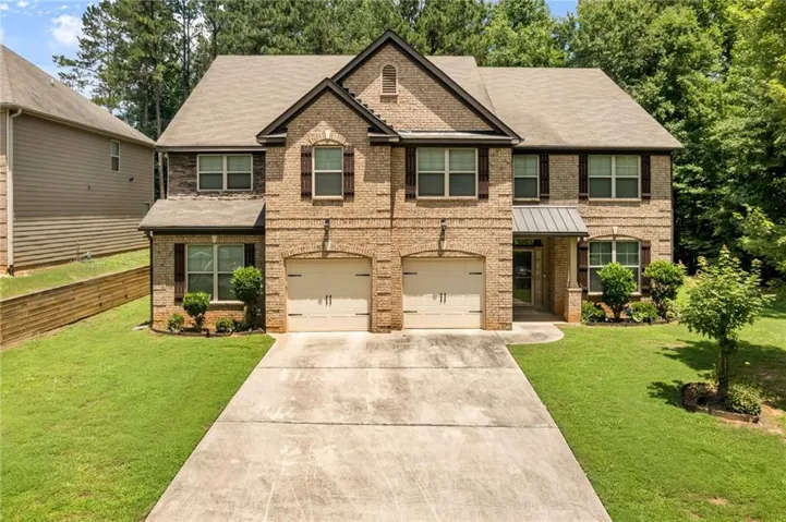 Brick exterior with stone accents, featuring a two-car garage, dark-framed windows, and decorative shutters