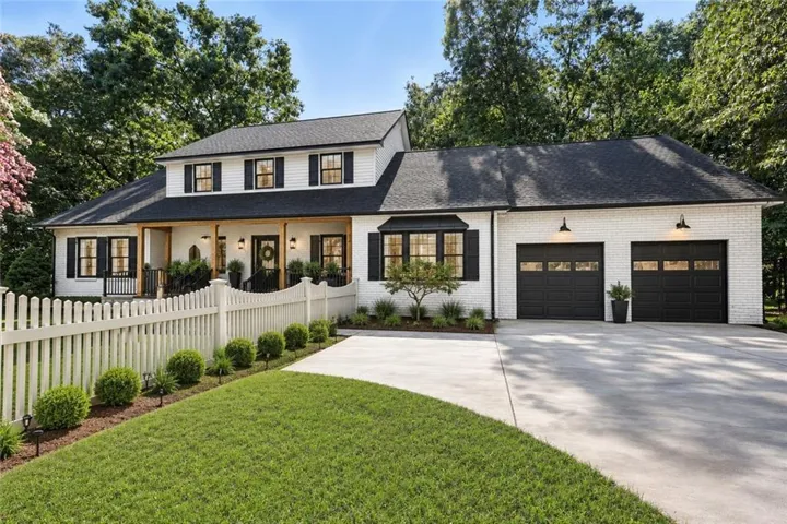 White brick exterior with black shutters and a dark shingle roof