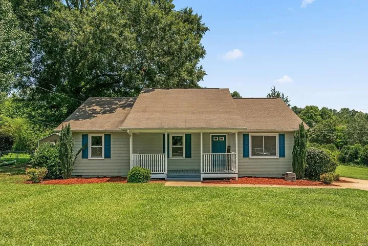 Single-story residence featuring light gray siding with blue shutters and an inviting front porch with white railings