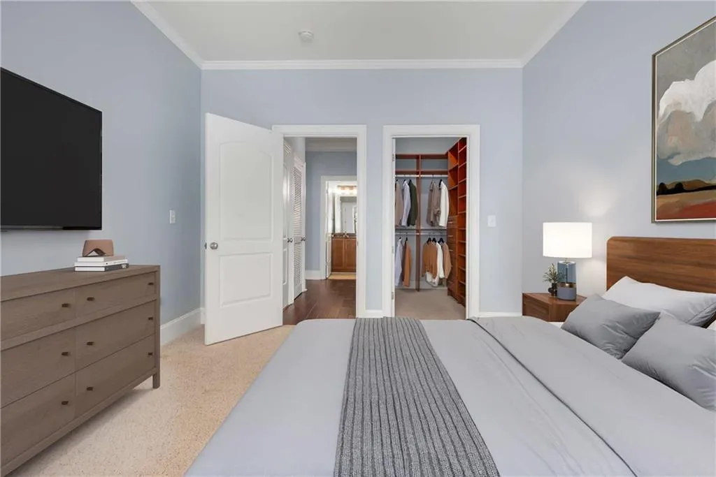 Bedroom with ornamental molding, a spacious closet, and light carpet