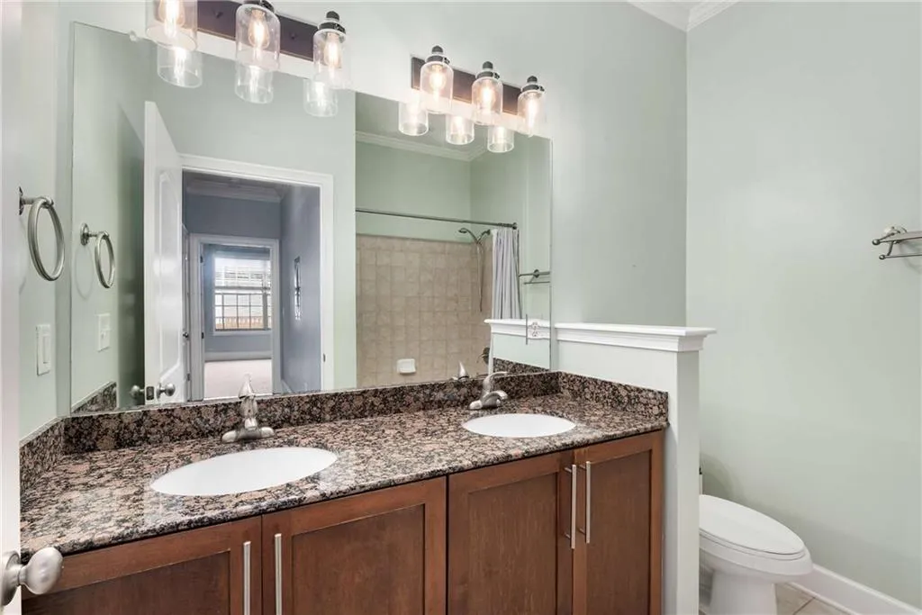 Bathroom with double vanity, crown molding, curtained shower, and light tile patterned floors