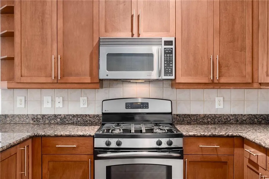 Kitchen with appliances with stainless steel finishes, brown cabinetry, and tasteful backsplash
