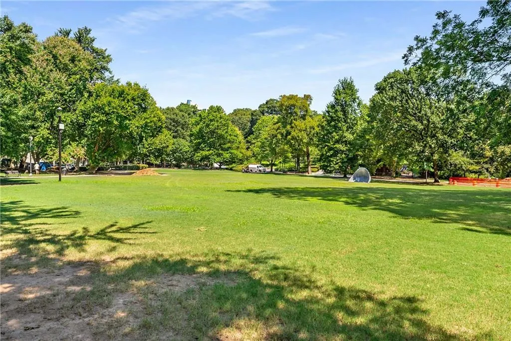 View of property's community featuring a lawn and view of wooded area