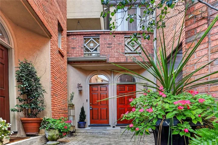 Brick exterior with arched entryways, paneled doors, and geometric window details