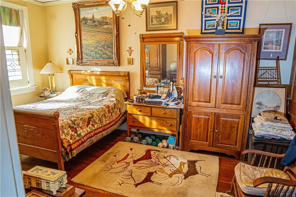 Bedroom featuring dark wood finished floors, ornamental molding, and a chandelier