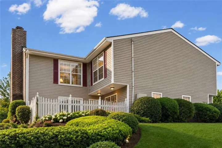 Siding exterior with a brick chimney and white picket fence